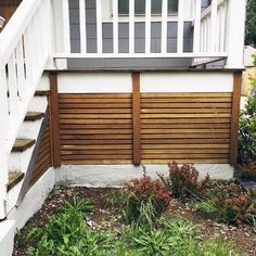 a wooden fence in front of a house with plants growing on the ground next to it