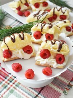 raspberries and cream filled pastries on a white plate with pine sprigs