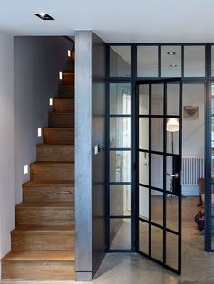 an open door leading to a living room with stairs and lights on the side of it