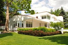 a large white house sitting on top of a lush green field next to a tree