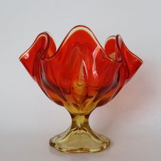 an orange glass vase sitting on top of a white table