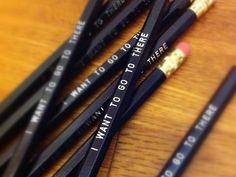 several pencils with writing on them sitting on a wooden table next to each other