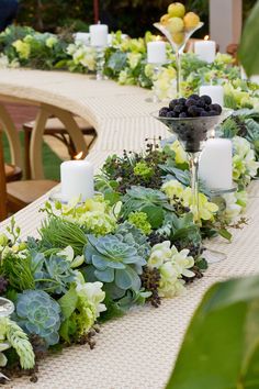 a long table with candles and flowers on it is set up for an outdoor dinner