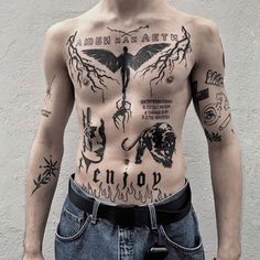 a man with tattoos on his chest standing in front of a white wall and wearing jeans