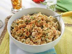 a white bowl filled with macaroni salad on top of a table next to two glasses