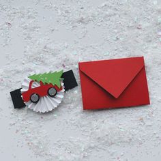 an origami christmas tree next to a red envelope with a car on it