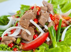 a white plate topped with lettuce, meat and vegetables on top of it