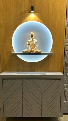 a buddha statue sitting on top of a shelf in front of a wall mounted cabinet