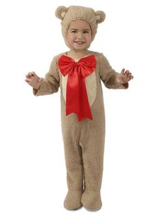 a little boy dressed in a teddy bear costume with a red bow on his head