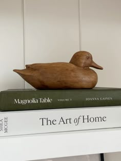 a wooden duck sitting on top of two books