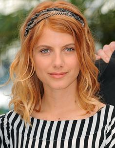 a woman with blonde hair wearing a black and white striped shirt is posing for the camera