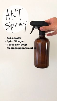 a hand holding a brown spray bottle with an anti - spray label on the side