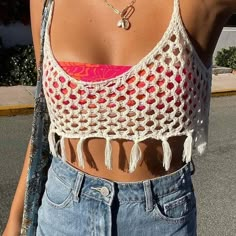 a woman wearing a crocheted crop top and denim shorts