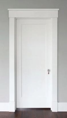 an empty room with a white door and hard wood floor