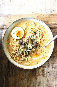 an overhead view of a bowl of soup with noodles, mushrooms and egg yolk