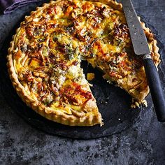 a quiche on a black plate with a knife