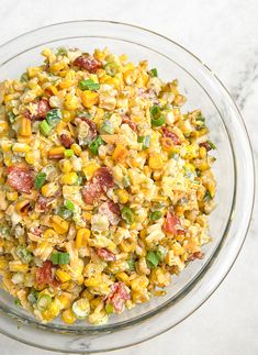 a glass bowl filled with corn salad on top of a table