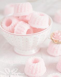 small pink sugar cubes in a bowl on a white tablecloth next to flowers