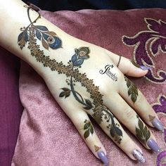 a woman's hand with henna tattoos on it and purple nail polishes