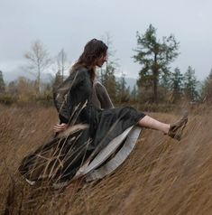 a woman is sitting in the tall grass