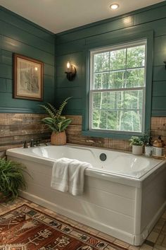 a large white bath tub sitting in a bathroom next to a window with green walls