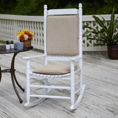 a white rocking chair sitting on top of a wooden deck next to a small table