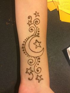 a woman's arm with a tattoo on it that has stars and crescents