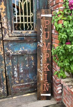 a wooden sign that says pumpkin on it next to a brick building with flowers in the background