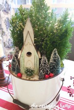 a white bucket filled with christmas trees and a small house