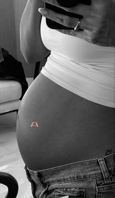 a pregnant woman holding a cell phone in her right hand and looking at her stomach