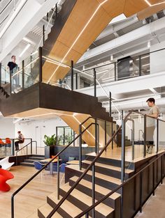 two people are walking up the stairs in an office building with wood and metal railings