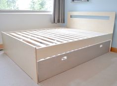 an empty bed frame in a bedroom with blue walls and carpeted flooring,