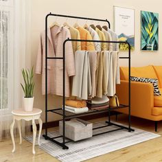 a white rack with clothes on it next to a couch