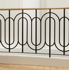 an iron and wood railing in a room with hard wood flooring on the side