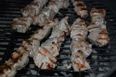 several skewers of meat cooking on a grill