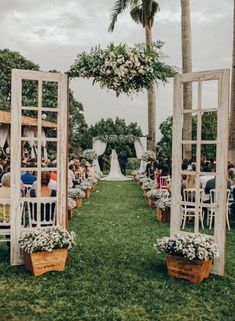 an outdoor wedding ceremony with white chairs and flowers on the aisle, surrounded by palm trees