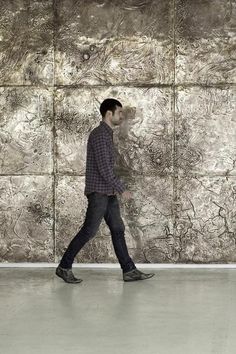 a man walking in front of a stone wall