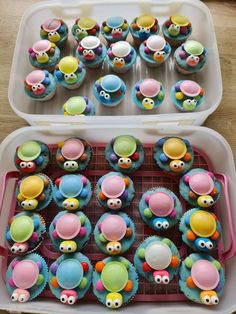 cupcakes decorated with colorful icing and decorations in a plastic container on a table