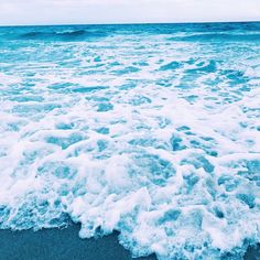 the water is foamy on the beach and it looks like waves are coming in