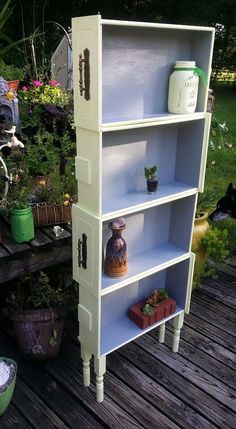 a white bookcase with pots and plants on it