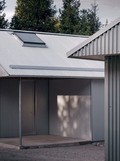 an empty building with metal roofing and two open doors on the side of it