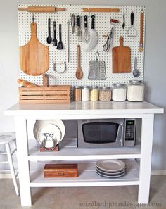 a white kitchen island with utensils hanging on the wall and various cooking tools