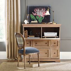 a chair sitting in front of a desk with a painting on it's wall