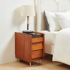 a nightstand with a record player on it next to a bed