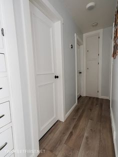 an empty hallway with white doors and wood flooring is pictured in this image from the front door