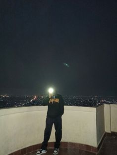 a man standing on top of a roof at night with a flashlight in his hand