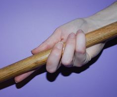 a person's hand holding onto a wooden stick on a purple background with light