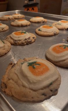 cookies with orange and white frosting are on a baking sheet, ready to go into the oven