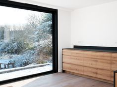 a kitchen with wooden cabinets and sliding glass doors that look out onto a snowy forest