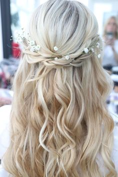 the back of a woman's head with long blonde hair and flowers in her hair